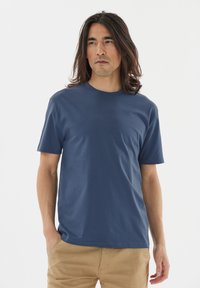 Marinblå t-shirt med kort ärm i mjukt tyg, med rund hals och normal passform, ihop med ljusbeiga byxor.