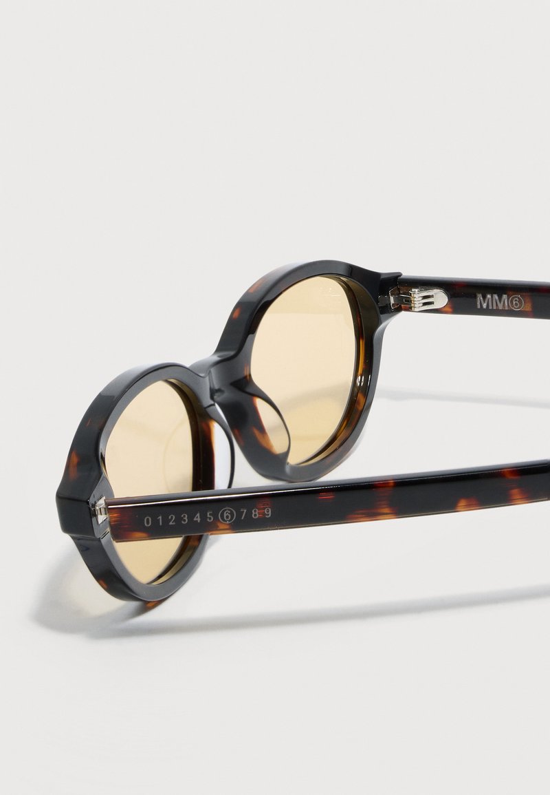 Lunettes de soleil rondes en écaille de tortue avec verres jaunes, charnière métallique visible et logo MM6 sur la branche.