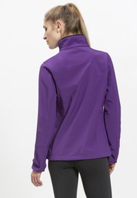 Lilla zip-up jakke med høj krave, lavet af et glat, strækbart materiale; har sømdetaljer og tætsiddende ærmer.