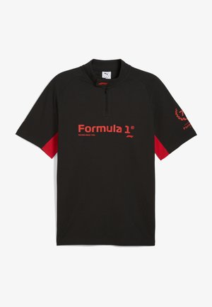 Črna majica s kratkimi rokavi z rdečimi akcenti na rokavih. Ima četrt-zadrgo in rdeč logotip "Formula 1" nad napisom "Racing Since 1950."