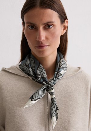 Silk scarf featuring a floral design in gray and white, tied neatly around the neck, worn with a light-colored zip-up hoodie.