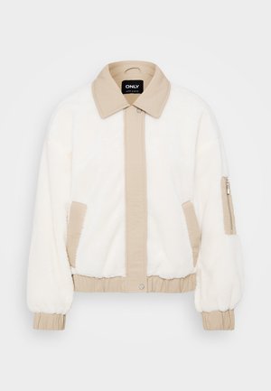 Faux fur jacket in ivory with a beige collar and front panel. Features elastic cuffs, side pockets, and a zippered arm pocket for storage.