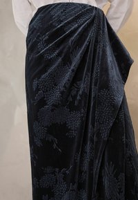 Navyblauer Samtrock mit strukturierten floralem Stickereien, drapierten Details und sanftem Schimmer.