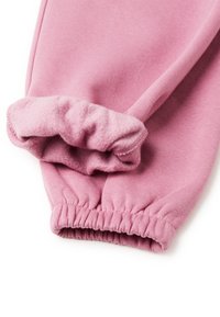 Růžové tepláky mají elastické manžety a měkkou fleece podšívku. Tkanina je texturovaná a mírně žebrovaná, což zajišťuje pohodlí a teplo.