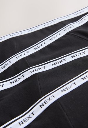 Melnas audums ar baltu tekstu "NEXT" un svītrām. Gluda faktūra ar šūtām detaļām un ģeometrisku rakstu, ko veido līnijas.