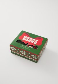 Boîte verte avec un ruban rouge, étiquetée "HAPPY SOCKS". Contient deux paires de chaussettes en tricot, décorées d'un motif festif.