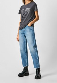 Gray t-shirt with "Pepe Jeans" text in rhinestones, paired with light blue straight-leg jeans and black waterproof ankle boots.