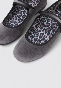 Bailarinas de tela gris con punta redonda, ribete negro y un diseño de estampado de leopardo en la plantilla. Textura suave, diseñadas para un uso cómodo.