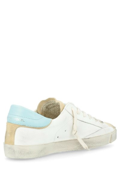 Sneaker in pelle bianca con accenti blu e beige, pannello posteriore testurizzato e chiusura con lacci. Suola consumata, cuciture visibili e design minimalista.