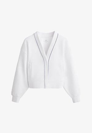 Biała krótka kurtka z dekoltem w serek, długimi rękawami, bocznymi kieszeniami oraz kontrastowym granatowym szwem wzdłuż zapięcia. Gładka tekstura materiału.