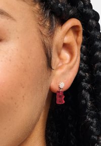 Rosa Gummibär-Ohrringe mit klarem Kristall-Stecker. Die Ohrringe haben eine verspielte, strukturierte Form und hängen zart vom Ohr.