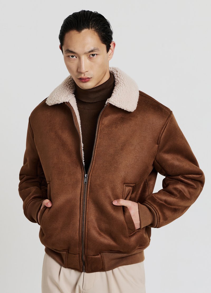 Giacca bomber marrone con collo in shearling beige, chiusura con zip, tasche laterali e polsini a coste. Texture liscia e vestibilità comoda.