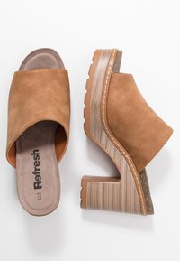 Escarpins en suède marron à plateforme, avec un large design de bout ouvert et une base en mousse texturée de couleur claire ; présentant un talon chunky et angulaire.