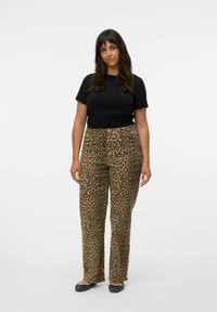 Crna majica s kratkim rukavima u kombinaciji s hlačama od leopard uzorka visokog struka, koje imaju opušteni kroj i ravni prednji dio. Crne balerinke upotpunjuju odjevnu kombinaciju.