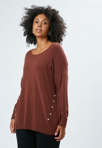 Brauner Strickpullover mit weitem Halsausschnitt und überschnittenen Schultern. Verfügt über dekorative Knöpfe an den Seiten sowie gerippte Bündchen und Saum.