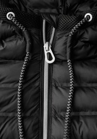 Section de veste rembourrée noire avec une fermeture éclair métallique, des cordons tressés et des accents en maille, avec une texture lisse et matelassée.