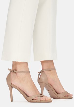 Sandali beige con tacco alto e cinturino sottile alla caviglia, open toe e una texture in pelle liscia. Tacco arrotondato e dettagli a taglio.