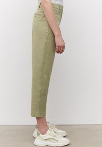 Lichtgroene, slim-fit broeken met een gladde textuur, met omslag onderaan en achterzakdetails, gecombineerd met wit-groene sneakers.