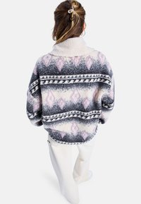 Pullover in pile con colletto alto, caratterizzato da un motivo geometrico nei toni del grigio, nero e lavanda, texture morbida e vestibilità ampia.