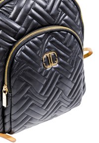 Zaino in pelle nera trapuntata con cerniere dorate e un logo doppio C dorato sulla tasca frontale.