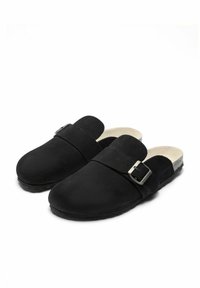 Svarta mocka klackar med stängd tå, justerbar spänne och en slät, vadderad innerfoder. Platt gummisula för stabilitet.