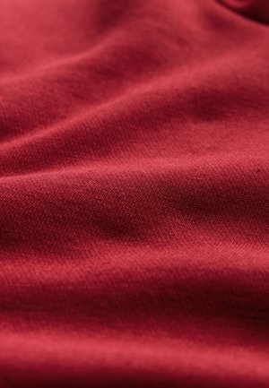 Rode stof met een gladde textuur, met subtiele weefpatronen en zachte plooien, die zachtheid en soepelheid aangeven.