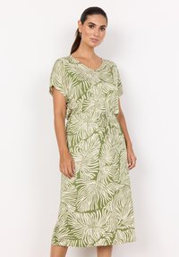 Grünes Kleid mit einem Blattmuster, kurzen Ärmeln und einem Kordelzug in der Taille. Hergestellt aus leichtem Stoff, knielang und mit lockerer Passform.