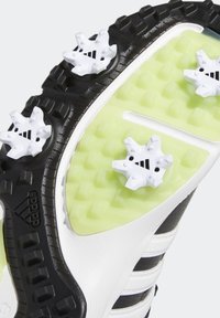 Czarny i biały spód buta z zielonymi akcentami, z białymi gwiazdkowymi wstawkami dla lepszej przyczepności. Teksturowane wzory z detalami logo Adidas.