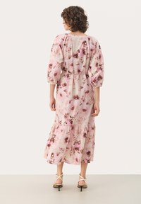 Robe midi florale avec des manches bouffantes, ornée de fleurs roses et brunes sur un fond clair, avec un ourlet en niveaux et une taille cintrée.