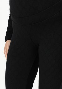 Sorte legging med en strukturert diamantmønster, glatt stoff og høy midje for en tett passform. Minimal søm og ingen synlige lukkinger.