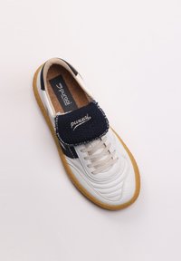Hvide sneakers med en tekstureret marineblå stofrem, lysebeige snørebånd og en gummisål, der har diskrete syninger og et logo.