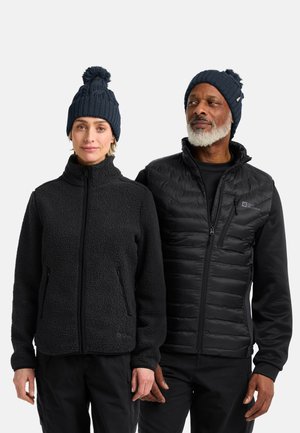 Black fleece jacket with a high collar on the left and a black insulated vest with horizontal stitching on the right. Both wear blue knit beanies.