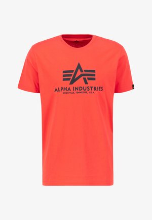 Punane puuvillane T-särk, mille esiküljel on must trükitud logo, millel on embleem ja tekst "ALPHA INDUSTRIES, KNOXVILLE, TENNESSEE, A.B.A.".