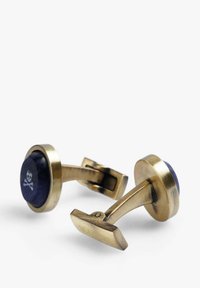 Gemelos de bronce con acentos de piedra azul, presentando un patrón de calaveras en las piedras y un cierre de palanca rectangular.