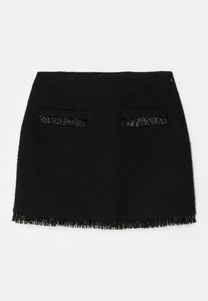 Crna suknja s teksturiranom tkaninom, koja ima dva prednja džepa i detalj resica na rubu. Opći oblik je uski A-linijski dizajn.