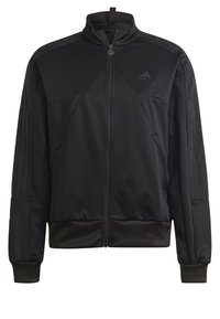 Chaqueta deportiva negra con cremallera, cuello alto, fabricada con tejido texturizado, dos bolsillos laterales y tres franjas verticales en las mangas.