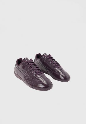 Paar dunkelviolette Low-Top-Sneaker mit geprägten kreisförmigen Mustern und passenden Schnürsenkeln auf schlichtem hellen Hintergrund.