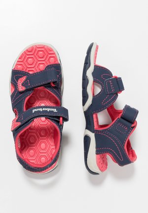 Kinder sandalen met klittenbandsluiting in marineblauw en roze, met een textuur van zeshoekige vormen op de zool, getoond vanaf boven en de zijkant op een witte achtergrond.