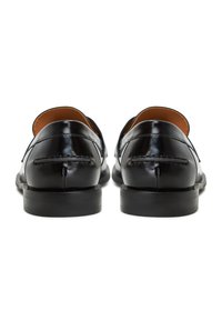 Zwarte leren schoenen met een gepolijste afwerking, met een lage hak en gestikte details aan de achterkant voor extra textuur.