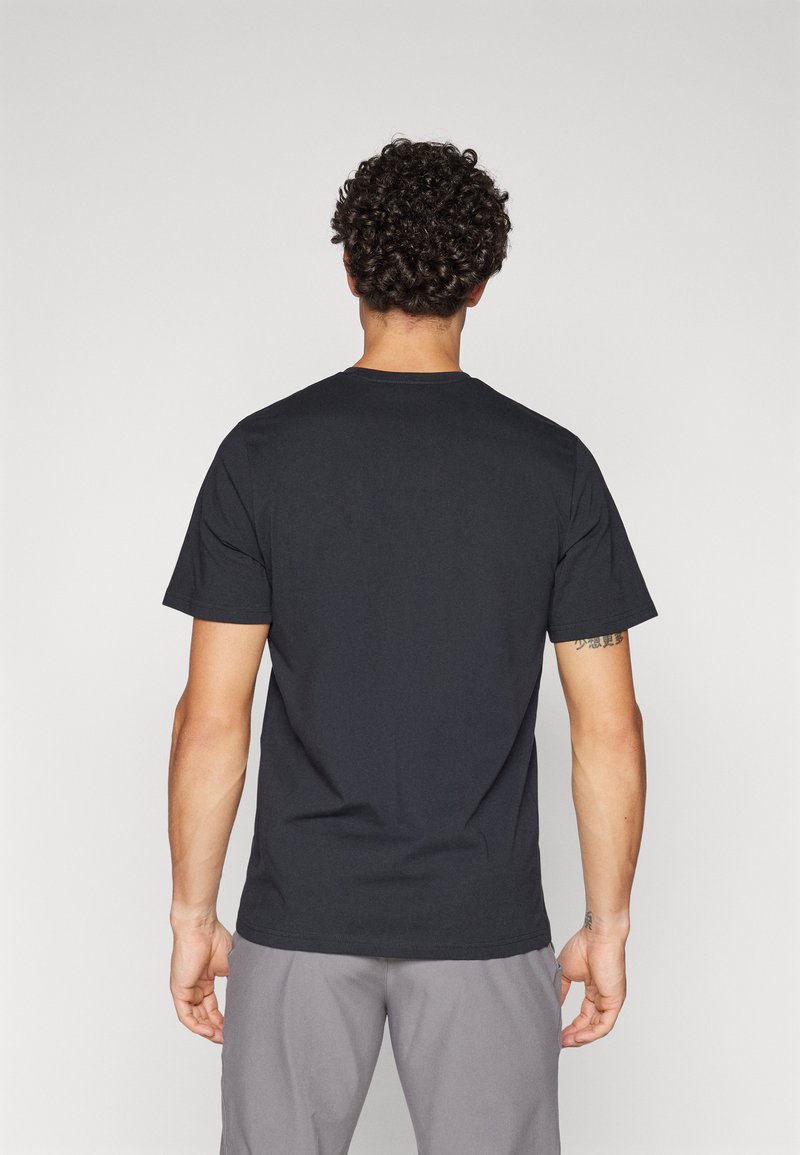 Schwarzes Kurzarm-T-Shirt mit rundem Halsausschnitt. Klassische Passform, glatte Textur und keine sichtbaren Logos. Getragen mit grauen Hosen.