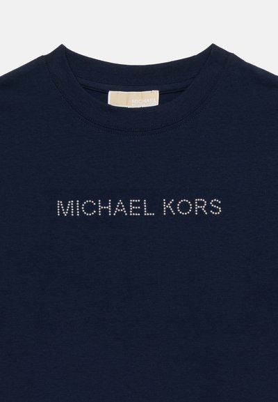 Μπλε ναυτικό μπλουζάκι με στρογγυλή λαιμόκοψη και το όνομα "MICHAEL KORS" γραμμένο με μικρές λευκές στρας στο στήθος, καθώς και μια μπεζ ετικέτα μάρκας στο εσωτερικό το υ γιακά.
