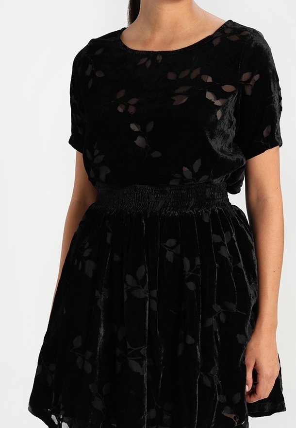 Robe en velours noir avec un motif floral, des manches courtes, une taille froncée, une jupe évasée et des détails transparents.