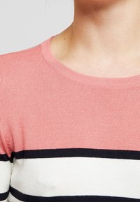 Kortärmad tröja med rund halsringning, tillverkad av stickat tyg i ljusrosa, med svarta och vita horisontella ränder.