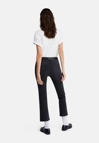 Svarta jeans i denim med smal passform och kort design, med medelhög midja, två bakfickor och subtila sömdetaljer.