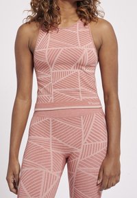 Ljusrosa träningslinne med geometriska mönster, en figurnära design och bred u-ringning. Tillverkat av stretchigt tyg för komfort.