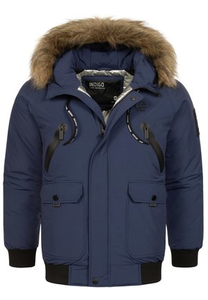 Tamno plavi jakni s kapuljačom obloženom krznom. Ima prednje džepove s zatvaračem i dugmima, rebraste manžete i sjajnu unutarnju oblogu.