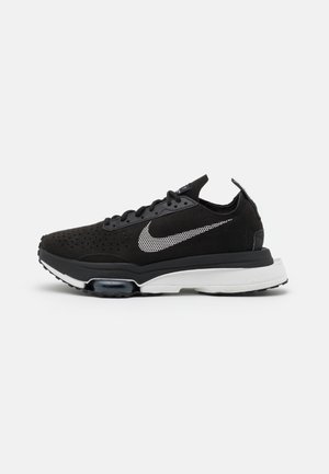 Black Nike sneaker with white dotted swoosh logo, perforated upper, black laces, and white cushioned sole on a plain background.
