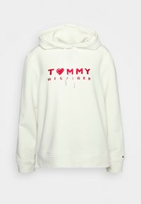 Biała bluza z kapturem, wykonana z mieszanki bawełny, z czerwonym sercem i logo "TOMMY HILFIGER" w wyraźnych literach na przodzie. Otwory rękawów wykończone ściągaczem.