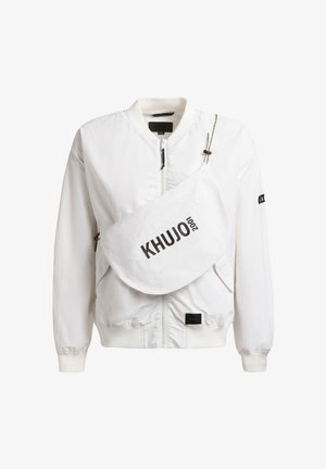 White bomber jacket with front zipper and large white crossbody bag labeled "KHUJO 2001" across the chest.