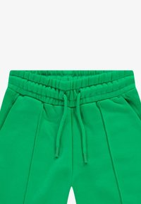 Groene joggingbroek van zacht materiaal met een elastische tailleband en trekkoord. Heeft zijknieten voor een relaxte pasvorm.